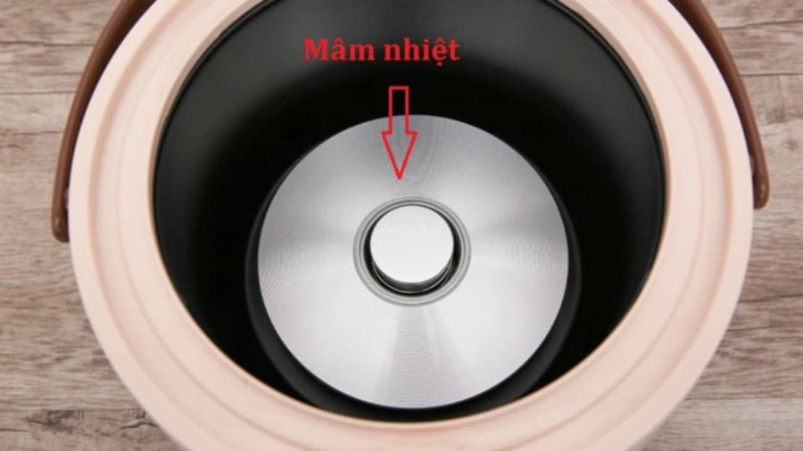 Mâm nhiệt nồi cơm điện, tức phần đĩa cứng đệm giữa đáy nồi và ruột nồi, được thiết kế hơi vồng theo một cung tròn